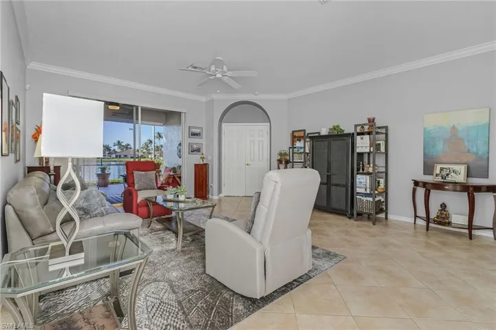 Living area with ornamental molding, light tile patterned floors, baseboards, and ceiling fan