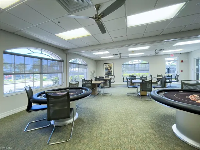 Exercise room with a ceiling fan, baseboards, carpet floors, and a paneled ceiling