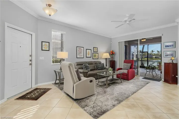Living area with a healthy amount of sunlight, light tile patterned flooring, and ornamental molding