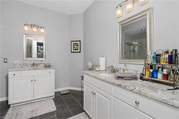 Bathroom with tile patterned flooring, two vanities, a stall shower, and a sink