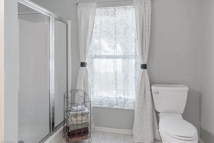 Bathroom featuring tile patterned flooring, a shower with door, and toilet