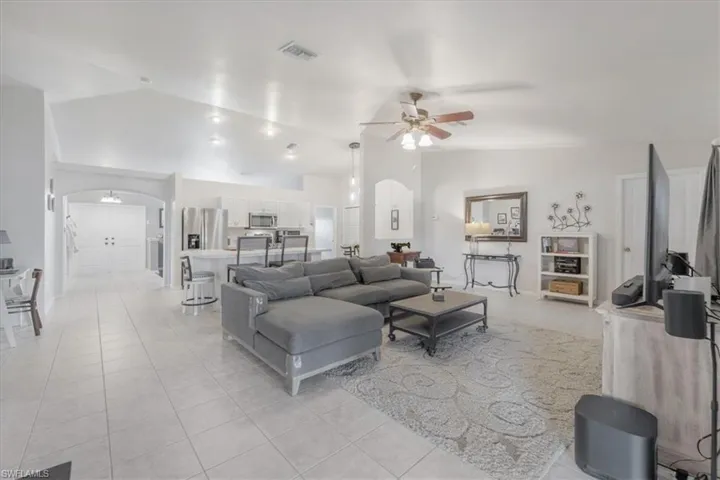Living room featuring light tile patterned flooring, ceiling fan, and lofted ceiling