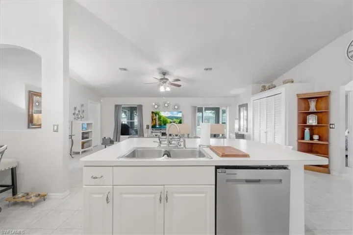 Kitchen featuring light tile patterned flooring, stainless steel dishwasher, ceiling fan, and white cabinets