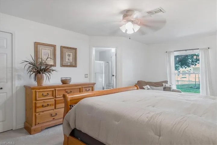 Bedroom with carpet, ensuite bath, and ceiling fan
