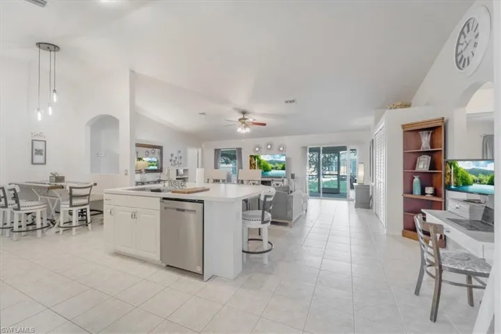 Kitchen with ceiling fan, hanging light fixtures, dishwasher, a center island, and vaulted ceiling