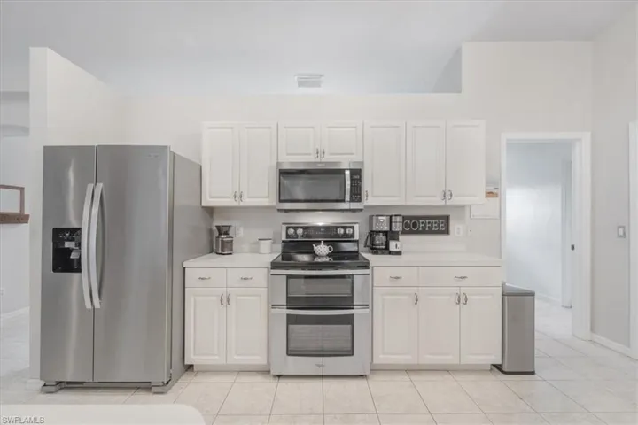 Kitchen with white cabinets, light tile patterned floors, and stainless steel appliances