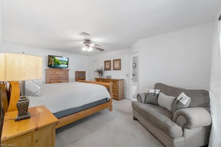Carpeted bedroom with ensuite bathroom and ceiling fan