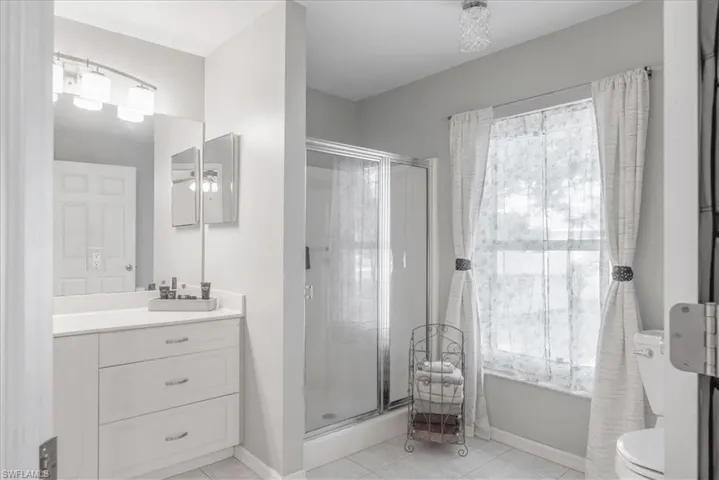 Bathroom with vanity, an enclosed shower, tile patterned flooring, and toilet