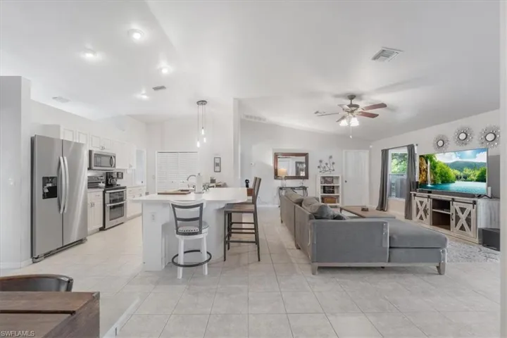 Living room featuring sink, light tile patterned floors, and ceiling fan