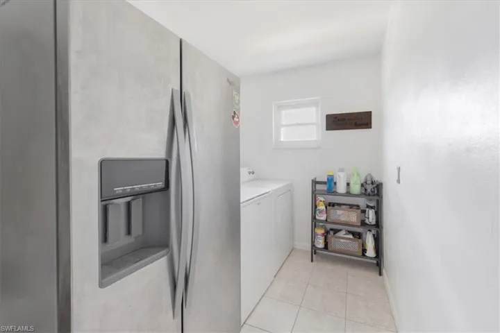 Laundry area featuring washing machine and clothes dryer and light tile patterned floors