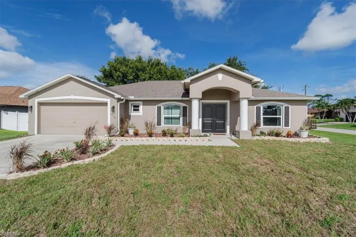Ranch-style house featuring a garage and a front lawn
