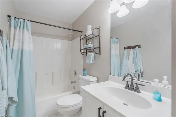 Full bathroom with tile patterned flooring, shower / bath combo, toilet, and vanity