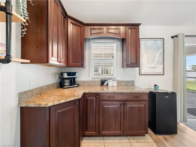 Kitchen featuring black fridge, light stone countertops, and light hardwood / wood-style flooring
