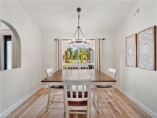 Dining space featuring light wood-type flooring, a notable chandelier, and vaulted ceiling