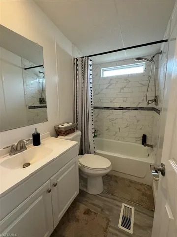 Full bathroom with shower / bath combo, hardwood / wood-style floors, toilet, and vanity with extensive cabinet space