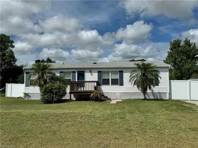 View of front of house featuring a front lawn and a wooden deck