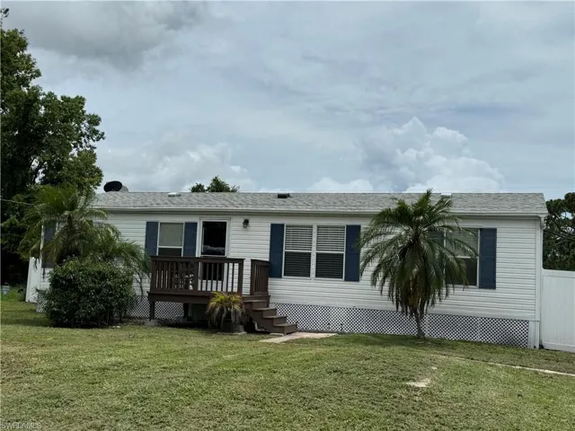 Rear view of house with a deck and a lawn