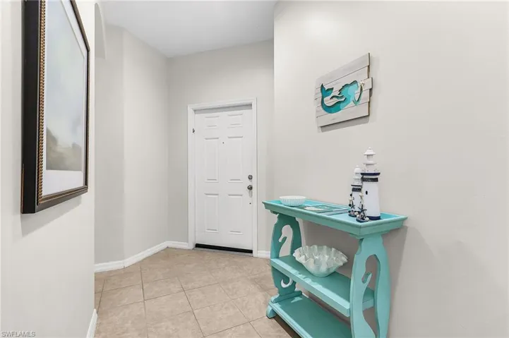 Doorway with tile patterned flooring and baseboards