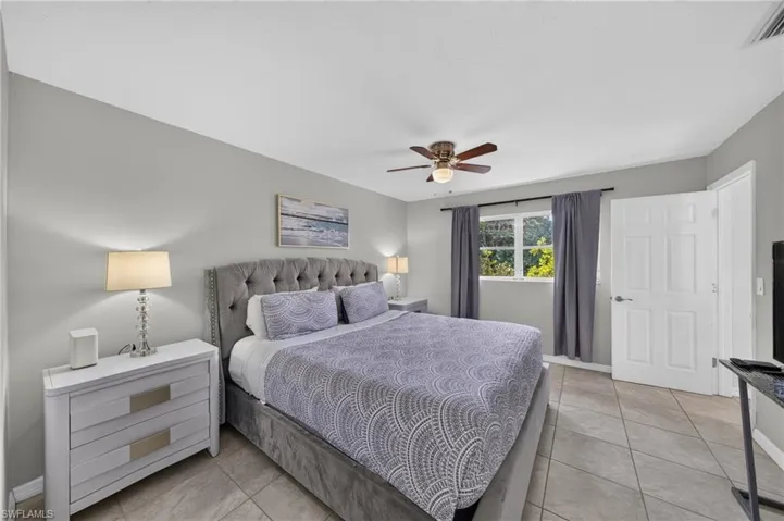 Room featuring tile flooring, a window with exterior foliage visible, and a ceiling fan