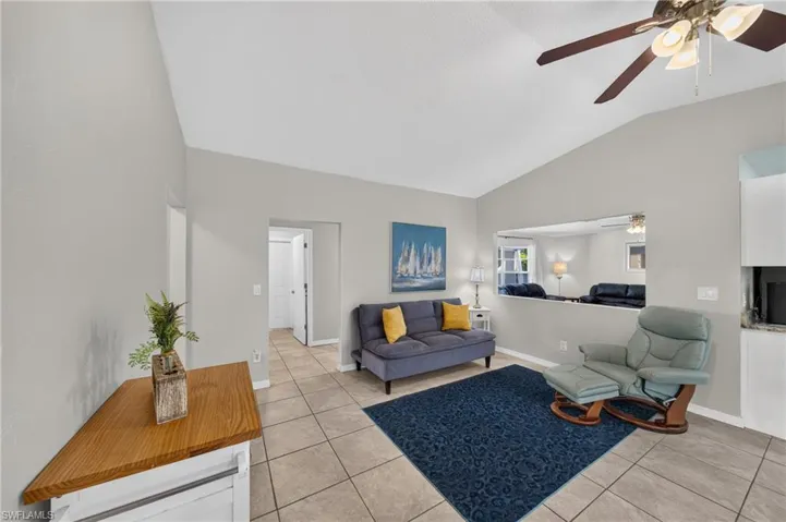 Vaulted ceilings, tile flooring, interior pass-through window, and a ceiling fan with integrated lighting