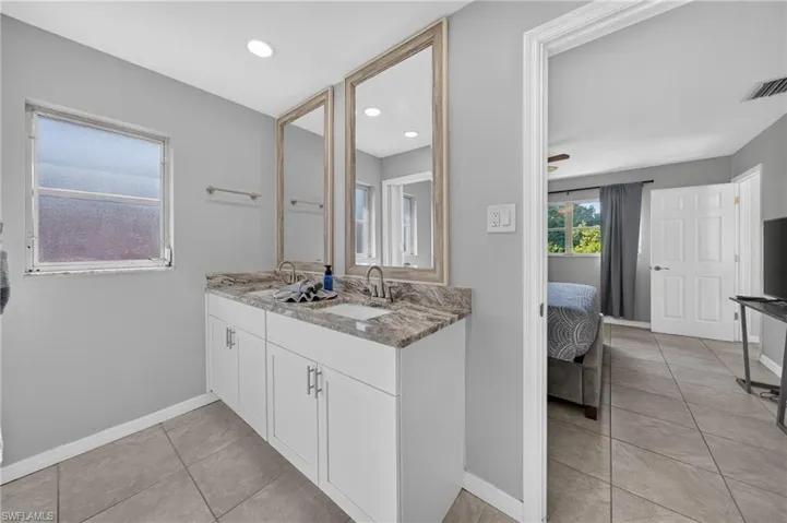 Dual vanity with stone-finish countertop, two undermount sinks, and two framed mirrors