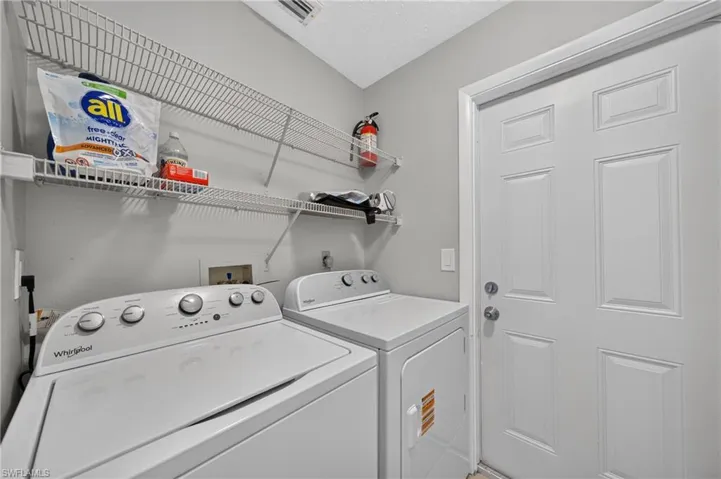 Utility room with integrated washer and dryer hookups, overhead wire shelving, and a paneled entry door