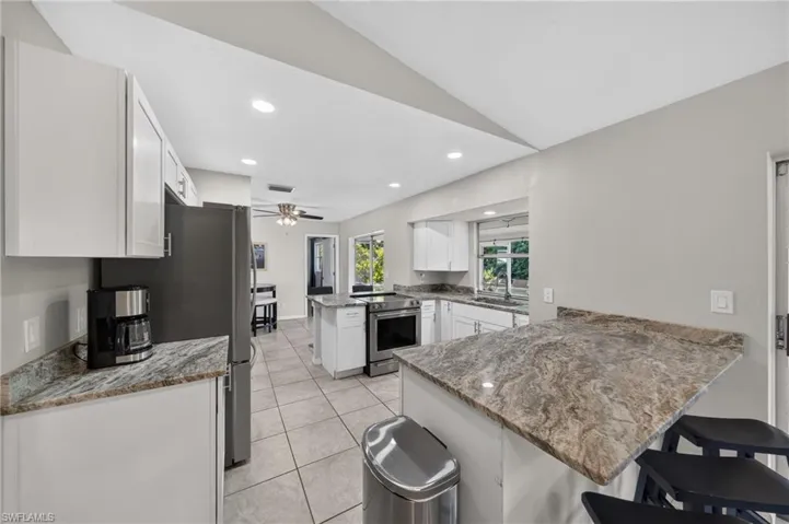 Kitchen featuring white cabinetry, stone-finish countertops, stainless steel appliances, and tile flooring