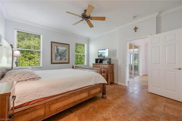 Tiled bedroom featuring ceiling fan and crown molding