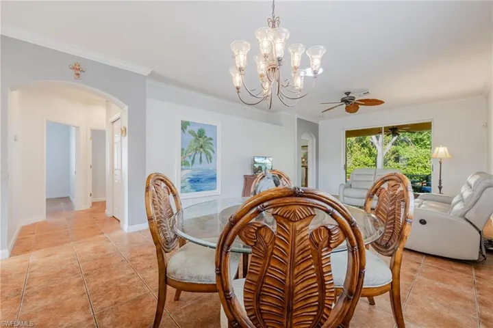 Dining room with ornamental molding, light tile flooring, and ceiling fan with notable chandelier