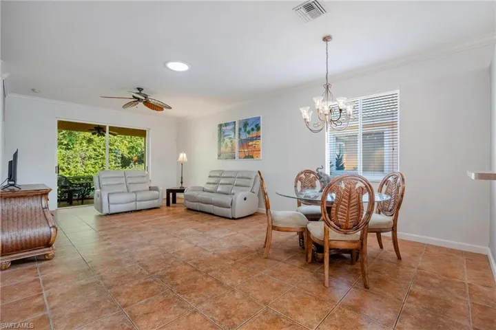 Tiled dining space with ceiling fan with notable chandelier and ornamental molding