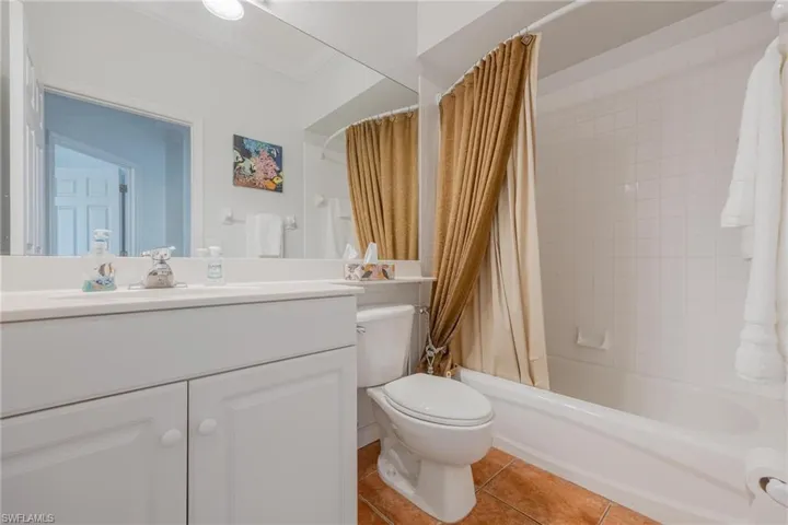 Full bathroom with crown molding, shower / tub combo, tile floors, large vanity, and toilet
