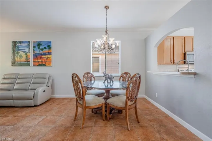Tiled dining space featuring a notable chandelier and crown molding