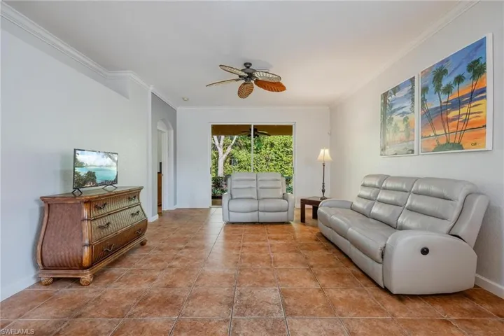 Tiled living room with ornamental molding and ceiling fan