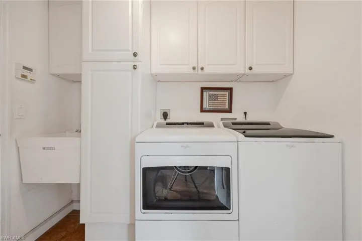 Washroom with cabinets, independent washer and dryer, dark tile floors, sink, and hookup for an electric dryer