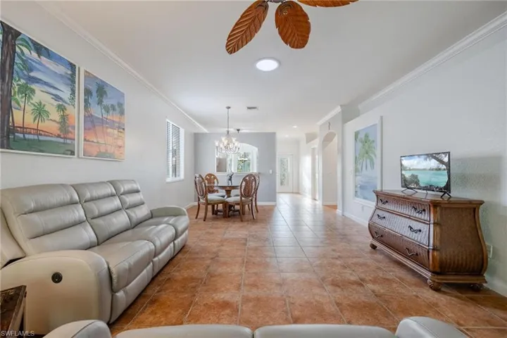 Tiled living room with ornamental molding and an inviting chandelier