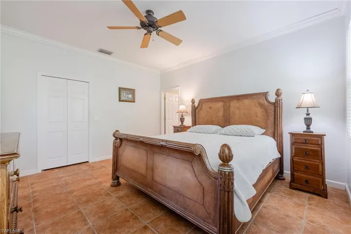 Bedroom with tile floors, crown molding, and ceiling fan