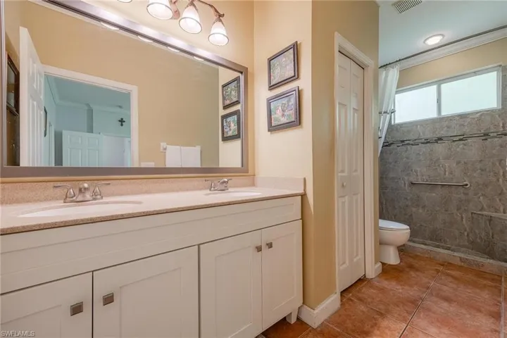 Bathroom with tile flooring, double sink, ornamental molding, toilet, and large vanity