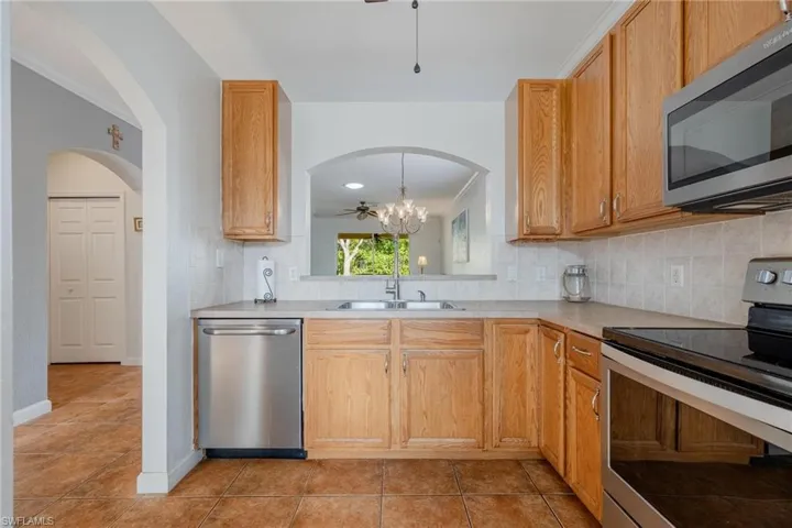 Kitchen featuring tasteful backsplash, crown molding, appliances with stainless steel finishes, sink, and light tile floors