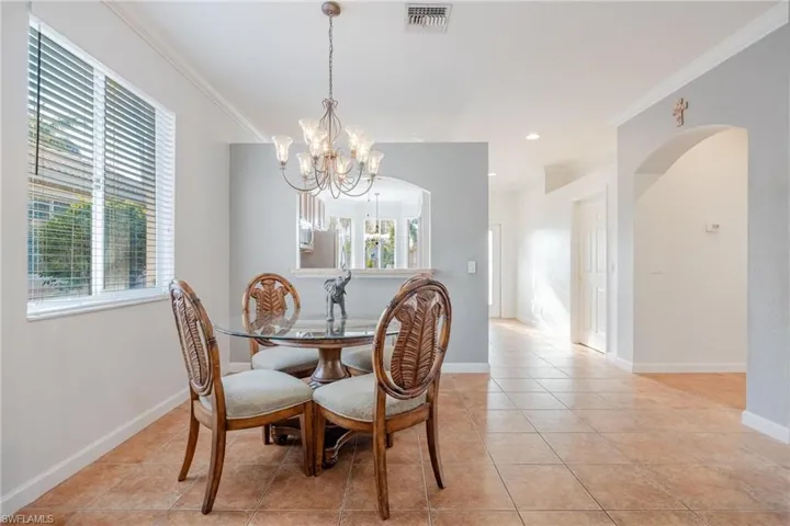 Tiled dining room with plenty of natural light, ornamental molding, and a notable chandelier