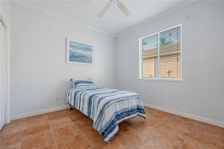 Tiled bedroom featuring crown molding and ceiling fan