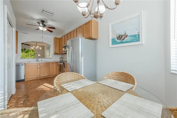 Tiled dining area featuring ceiling fan with notable chandelier and sink