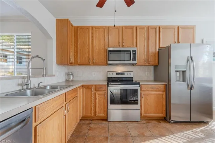 Kitchen with stainless steel appliances, ceiling fan, tasteful backsplash, sink, and light tile floors