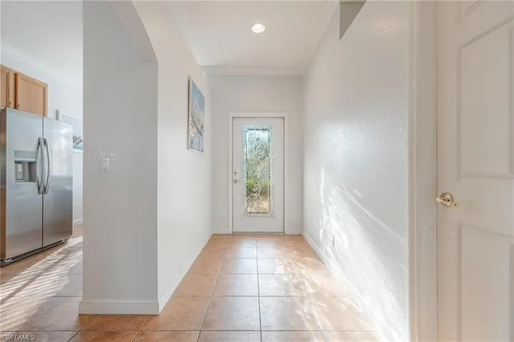 Entryway featuring ornamental molding and light tile floors