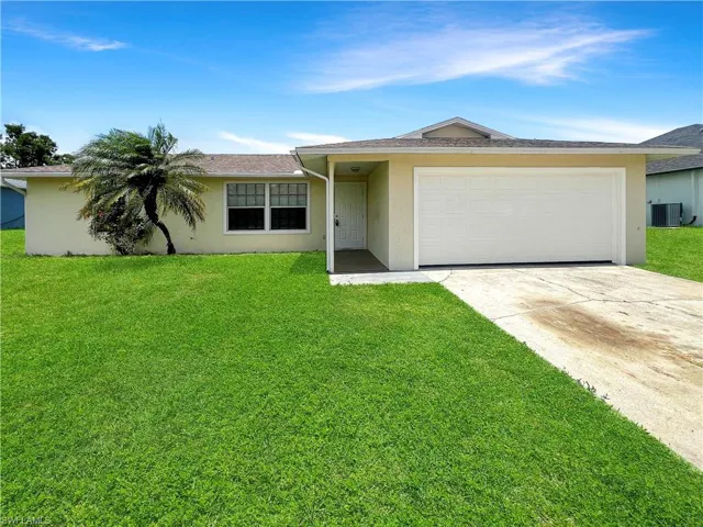 Ranch-style house featuring a garage, central air condition unit, and a front lawn