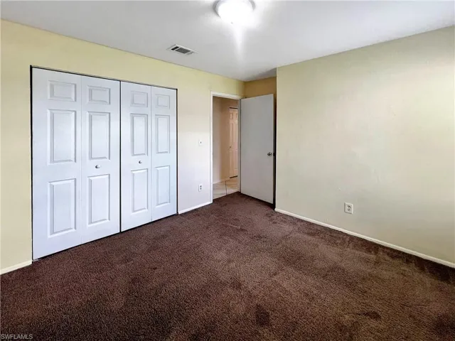 Unfurnished bedroom featuring dark colored carpet and a closet