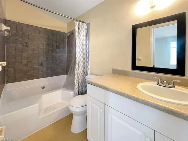 Full bathroom featuring toilet, vanity, tile patterned floors, and shower / bath combo with shower curtain