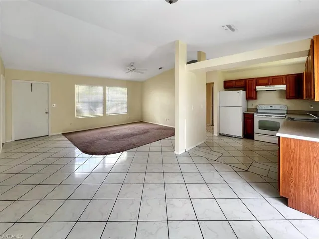 Kitchen with white appliances, lofted ceiling, sink, ceiling fan, and light tile patterned floors