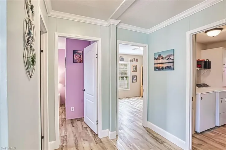 Corridor featuring light wood-style flooring, ornamental molding, and independent washer and dryer
