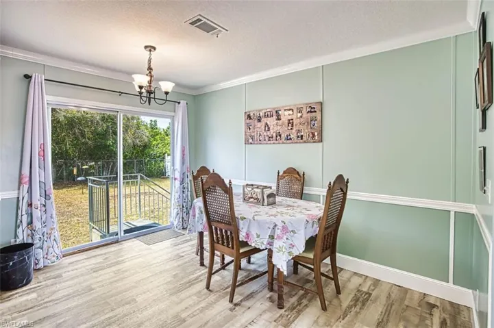 Dining area featuring a chandelier, a textured ceiling, light wood finished floors, and crown molding