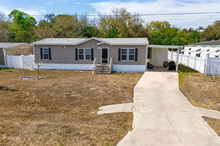 Manufactured / mobile home with concrete driveway and a carport